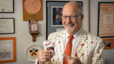 Frederick Strobel in his office, smiling while he holds a bag of candy snacks