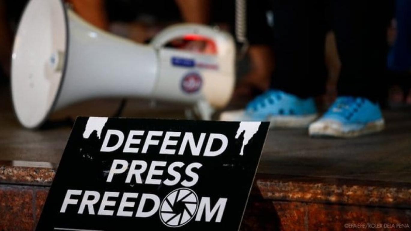 Bullhorn and sign that reads "Defend Press Freedom"
