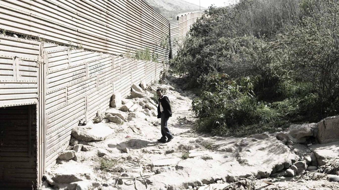 Man standing on sand and rock by a wall