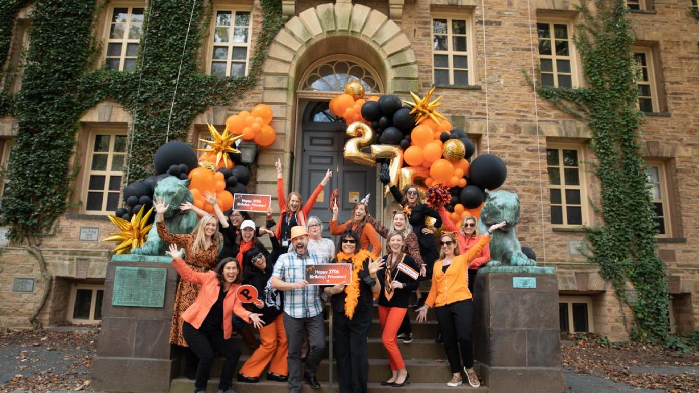 Staff members in front of Nassau Hall wearing orange and black