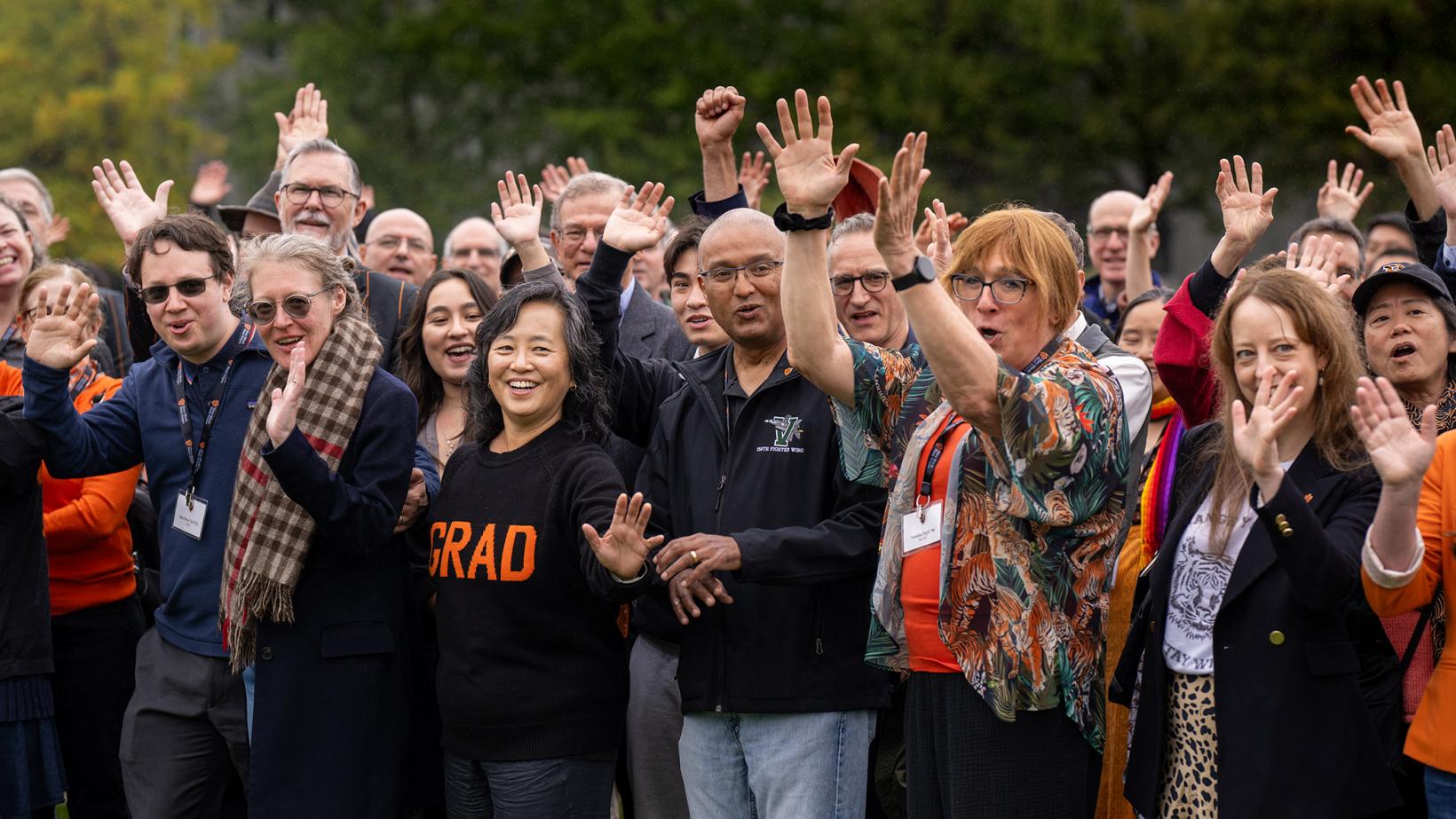 Alumni of the Graduate School woot and holler on Poe Field before a group photo during the Many Minds conference.