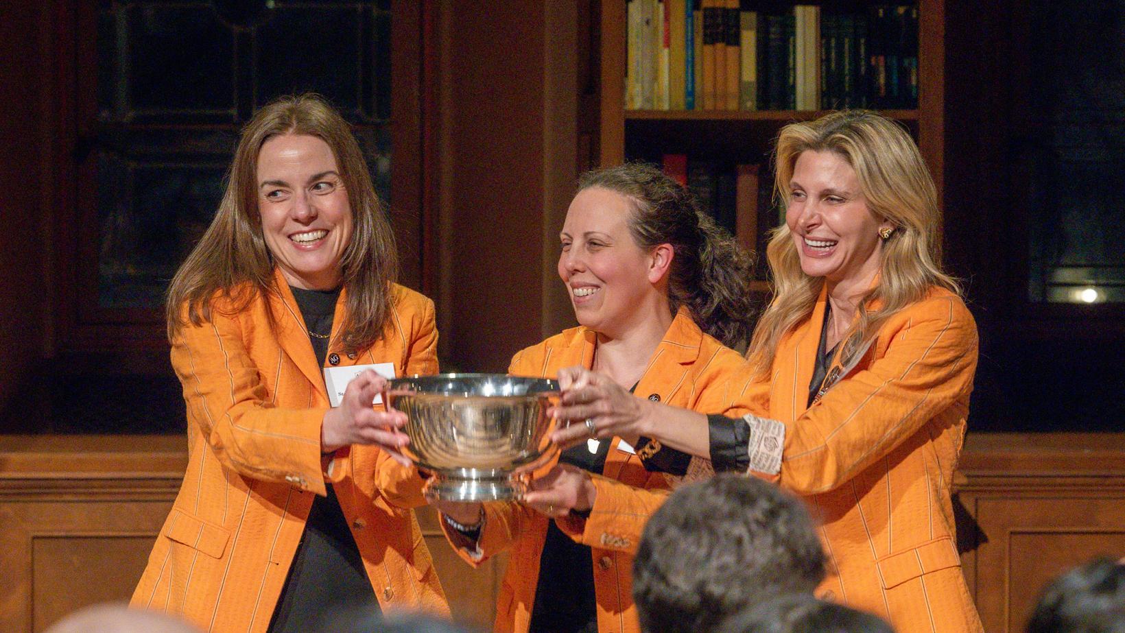 Wearing identical orange jackets, Tiffany Madigan, Stephanie Ramos and Alexis Moses proudly hold the Class of 1926 Trophy.