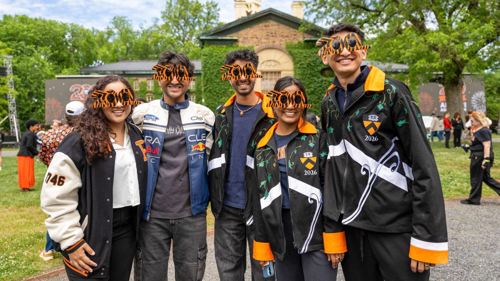 Five younger alumni wearing special 200 anniversary sunglasses while standing in front of Nassau Hall