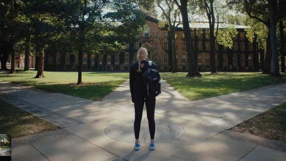 A female undergraduate looks at Nassau Hall, with her back to the camera.