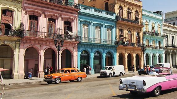 Scenic picture of Cuba with bright cars on the street and bright buildings in the background