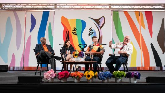 Four members of the Exploring LGBTQ+ Voices in Entertainment panel sit on the stage 
