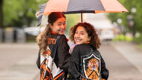 Two Princeton alumnae under an orange and black umbrella