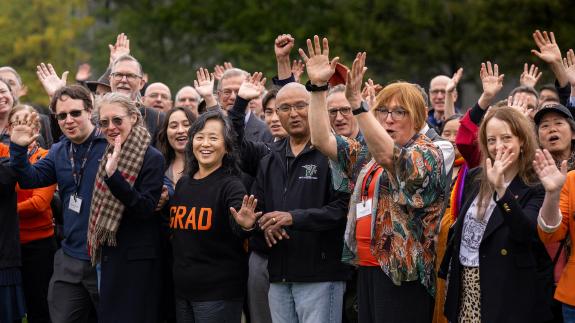 Alumni of the Graduate School woot and holler on Poe Field before a group photo during the Many Minds conference.