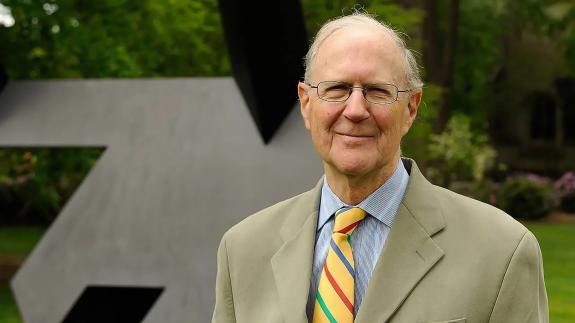 John Wilmerding, in tie and jacket, standing in front of the art installation near Prospect House.