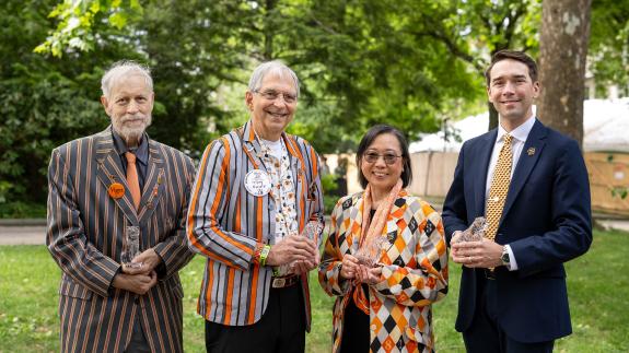Three men and one woman stand outside holding crystal tigers
