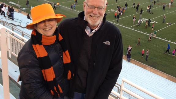 Bonnie Hewson and Chuck Marboe with a football stadium field in the background