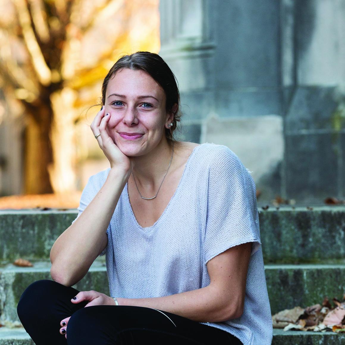 Ali Munson '21 seated on stone steps with stone building and tree in background