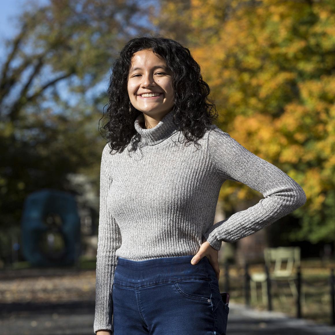 Emily Sanchez '22 standing on Princeton campus with fall foliage in background