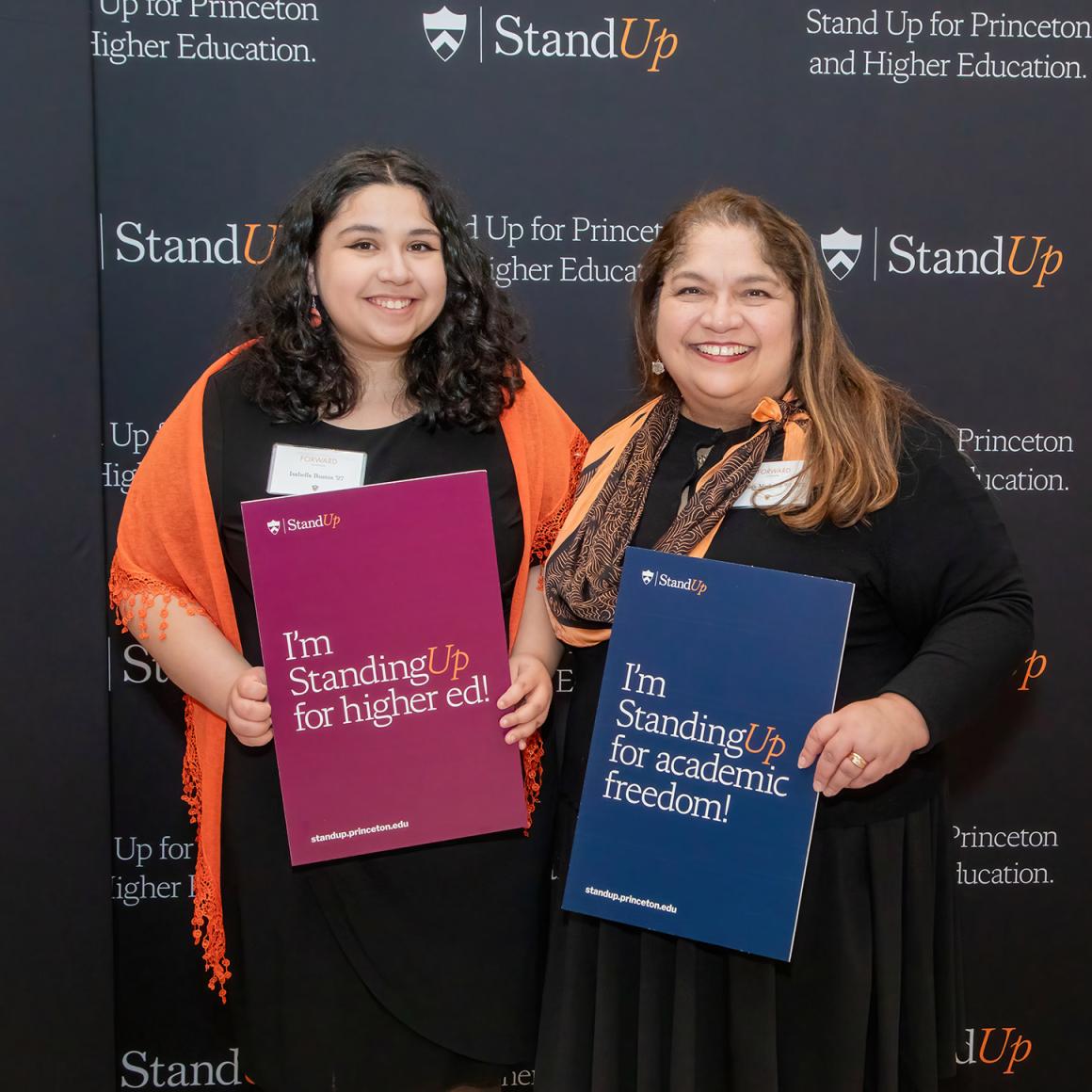Two alumni stand up for Princeton with signs supporting higher education.