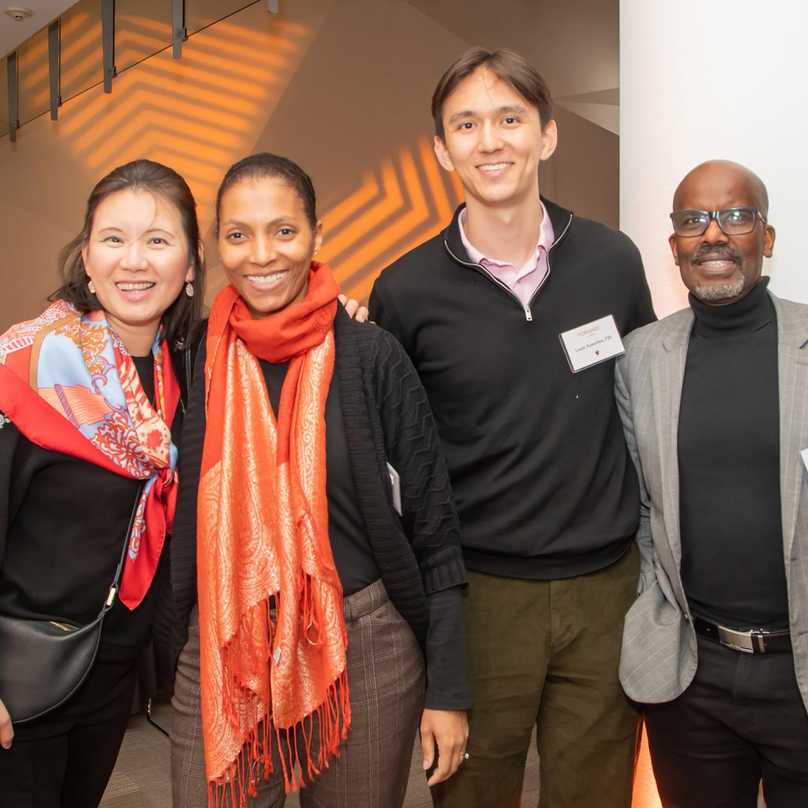 Four younger alumni wearing orange and black. 