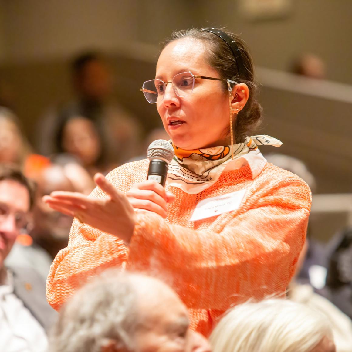 An alumna in the audience holding a mic poses a question.