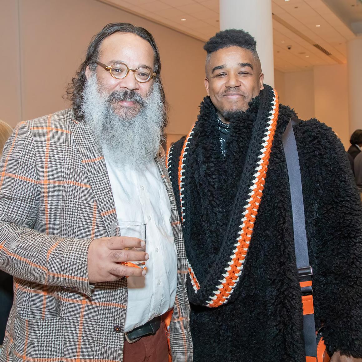 Two alumni dressed in stylish black and orange. 