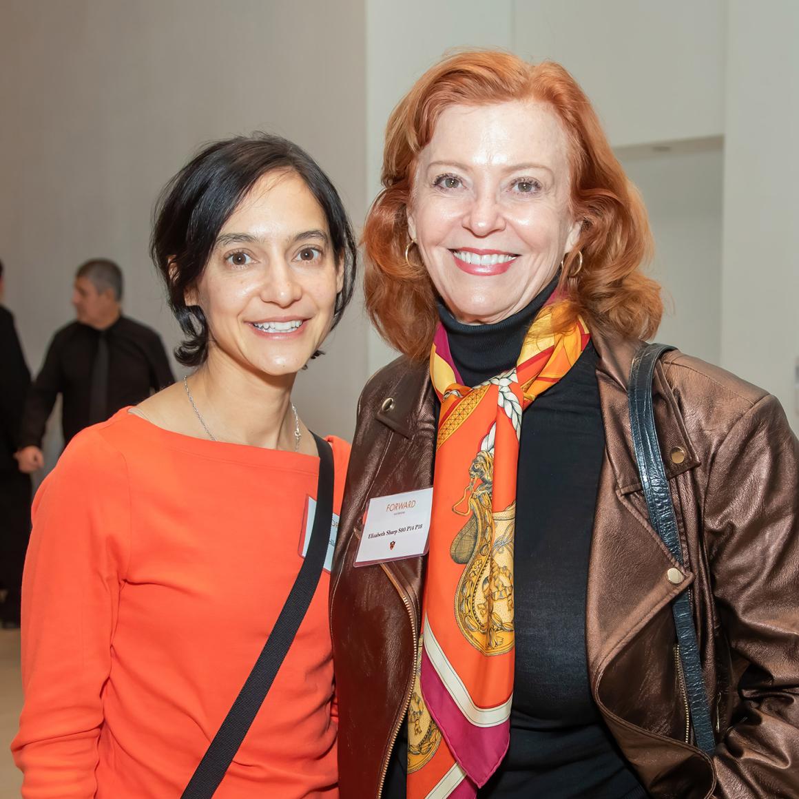 Two women posing in orange. 