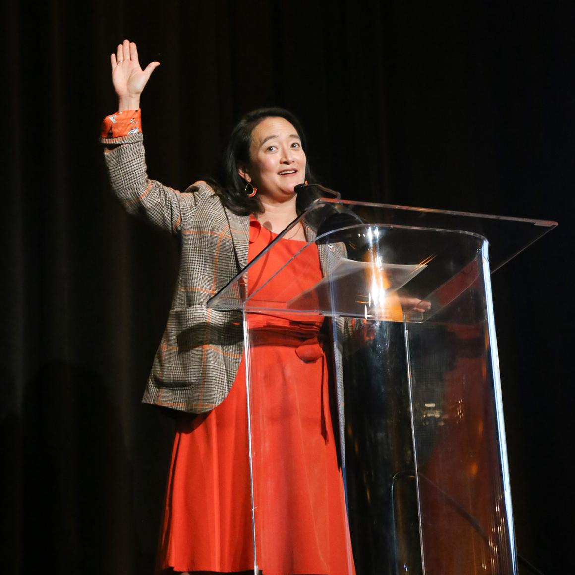 April Chou at a podium, dressed in orange