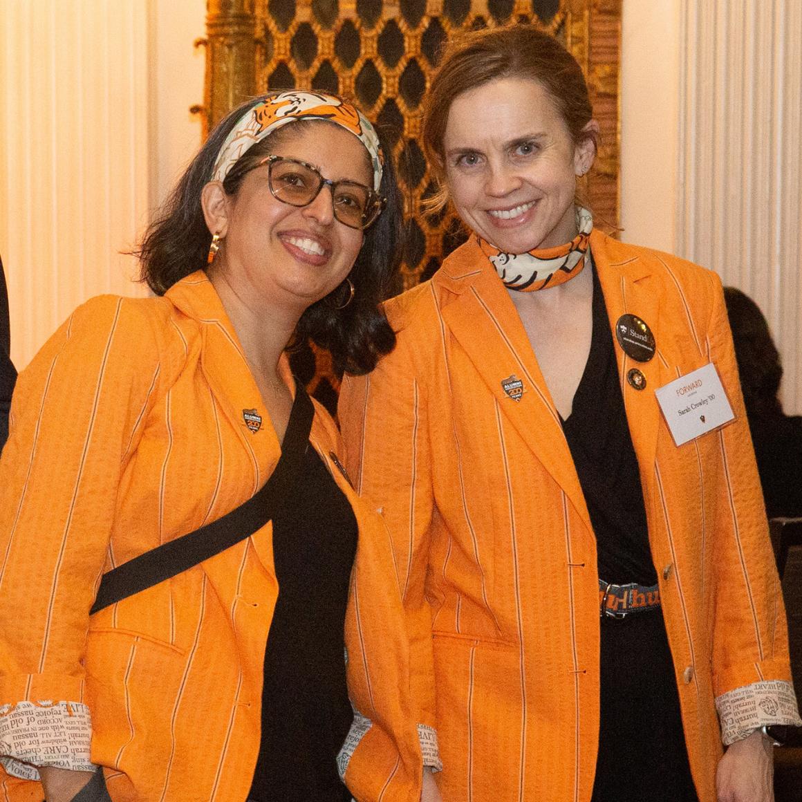 Two alumna in bright orange class jackets
