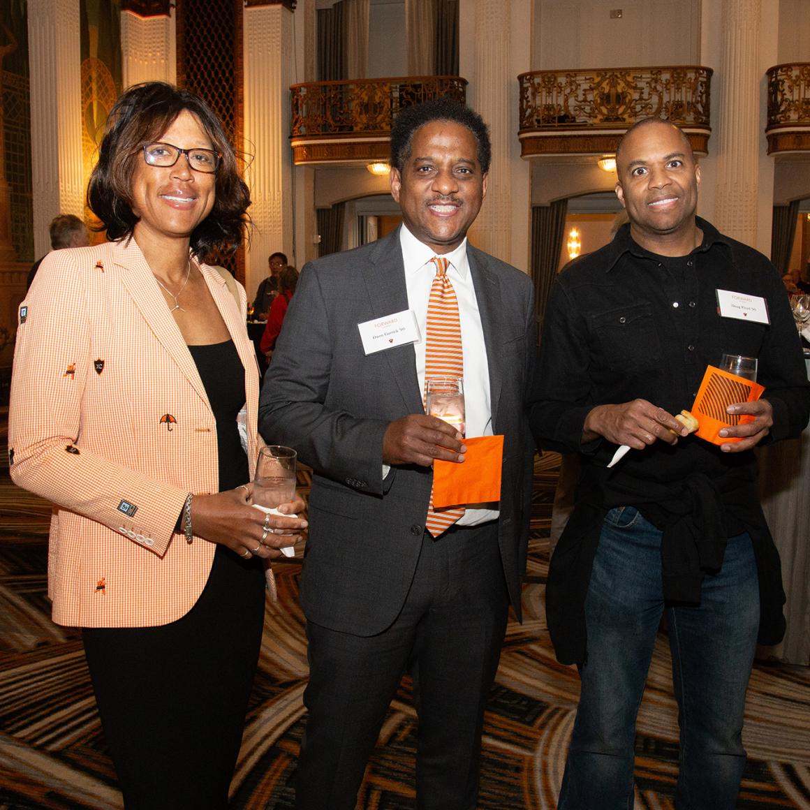 Three alumni, wearing orange 