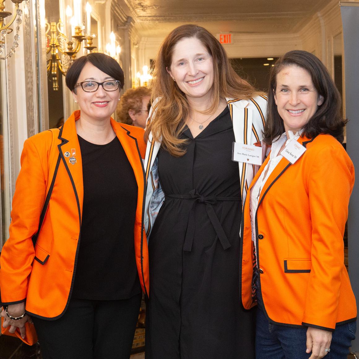 Three alumna dressed in orange
