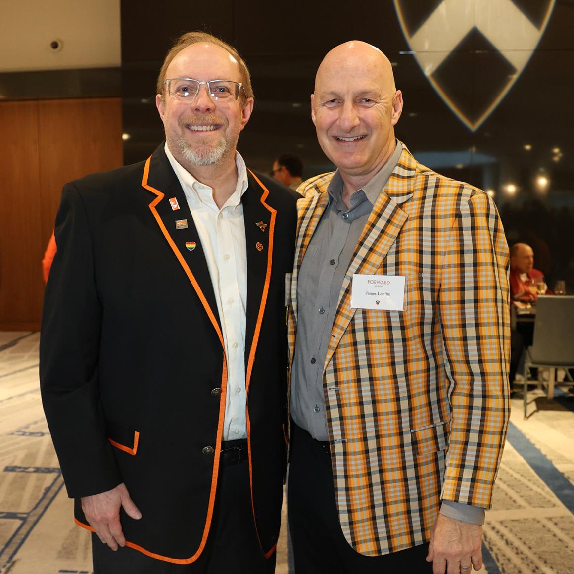 Two alumni wearing fancy class jackets