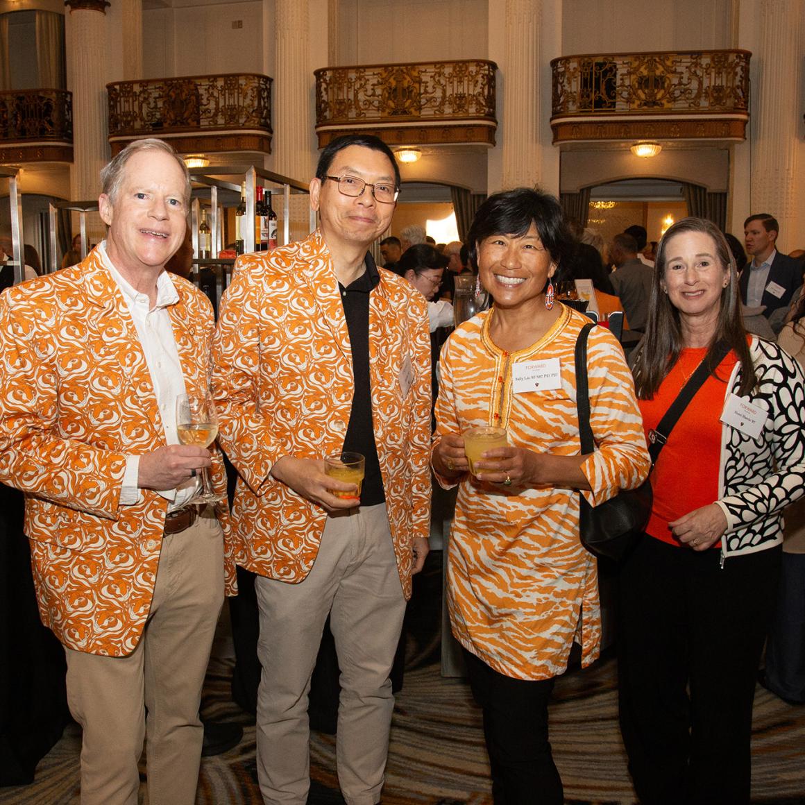 Four alums dressed in bright orange class jackets