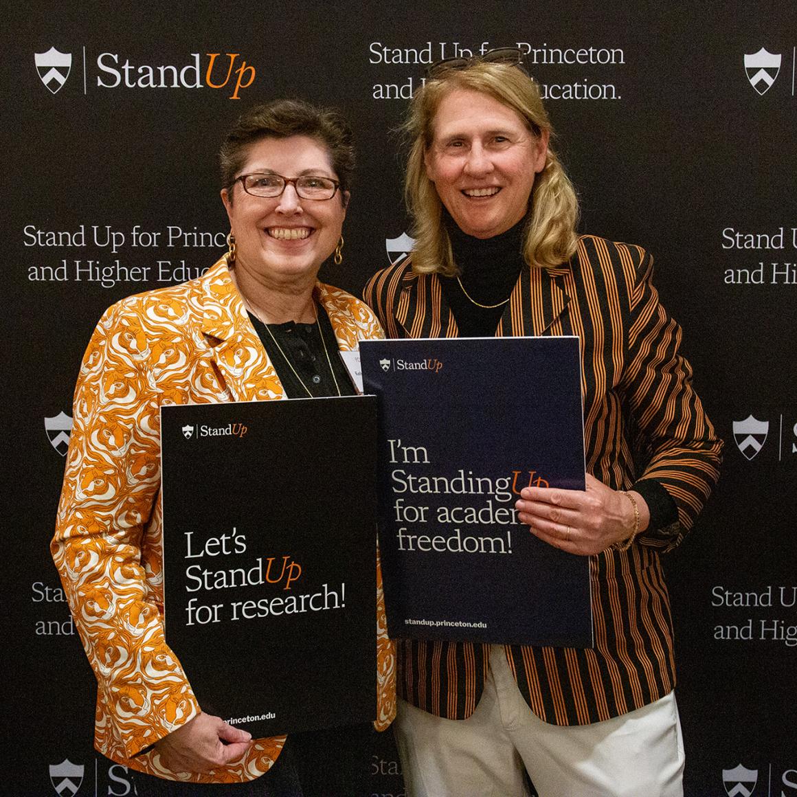 Two Princeton alums holding Stand Up for Princeton signs