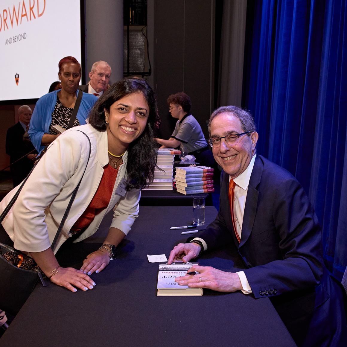 Christoper Eisgruber looks up from signing a copy his book for an alumna.