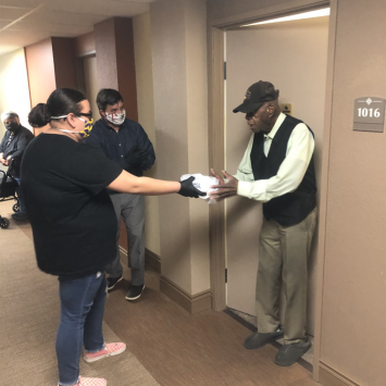Fresher Sacramento Volunteer Lucy handing a meal to Charles at his door