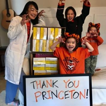 An adult and three youngsters imitate tiger grimaces and claws with PPE and thank you Princeton sign