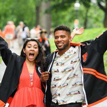 Two young alumni with arms in air in celebratory fashion.