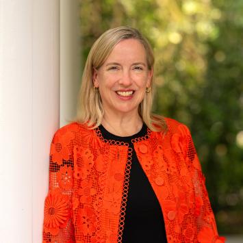 Profile of Jen Caputo, wearing an orange sweater