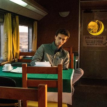 Jordan Salama writing in his notebook aboard a train