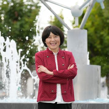 Mary Luo, dressed in red, smiling in front of a fountain