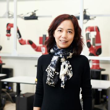 Fei-Fei Li, posing for the camera in a robotics lab
