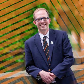 Andrew Houck smiling, dressed in blazer and tie. 