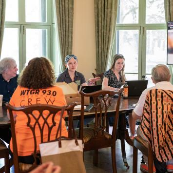 Advancement Communications staff speaks to alumni volunteers while seated at a table in Maclean House
