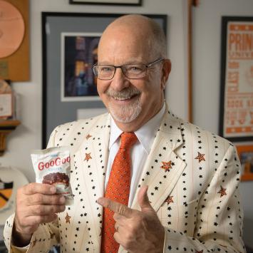 Frederick Strobel in his office, smiling while he holds a bag of candy snacks