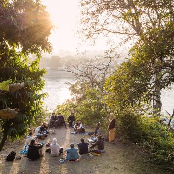 A group sits in a circle by a river
