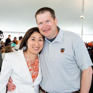 Doug and Susan Massick, arm in arm, under a tent at Reunions in 2023