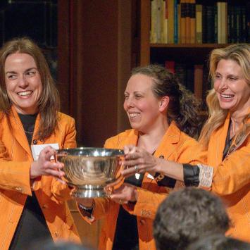 Wearing identical orange jackets, Tiffany Madigan, Stephanie Ramos and Alexis Moses proudly hold the Class of 1926 Trophy.