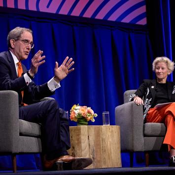 President Eisgruber, seated on stage alongside Weezie Sams, speaking to a packed hall.