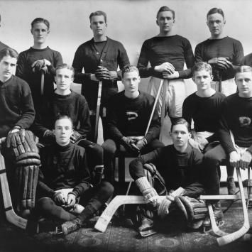 Black and white team photo of the Princeton ice hockey team, with Hobey Baker seated in the middle