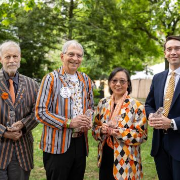 Three men and one woman stand outside holding crystal tigers