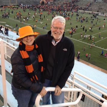 Bonnie Hewson and Chuck Marboe with a football stadium field in the background