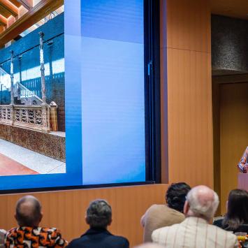 James Steward at a podium with a photo of the interior of the art museum on the screen to his left
