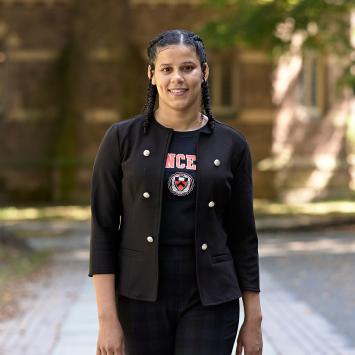 A smiling Princeton student walking near Nassau Hall. 