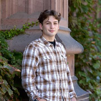 A Princeton student leaning against an Ivy-covered exterior.